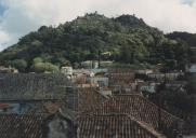Vila de Sintra tendo em primeiro plano os telhados do Palácio Nacional de Sintra, ao fundo a Serra com o Castelo dos Mouros.