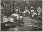 Pessoas em traje de cerimónia num lanche ao ar livre.