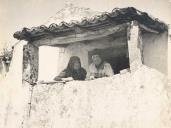 Casal de saloios em traje popular no alpendre de uma casa rural.