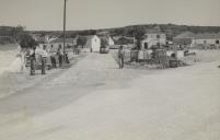 Trabalhadores na construção do Largo de Negrais com vista para casas saloias e um poço com nora.